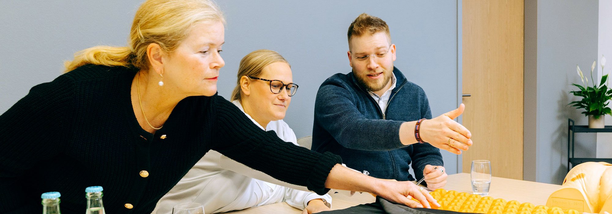 Carenetic employees discussing anti-decubitus aids at a table