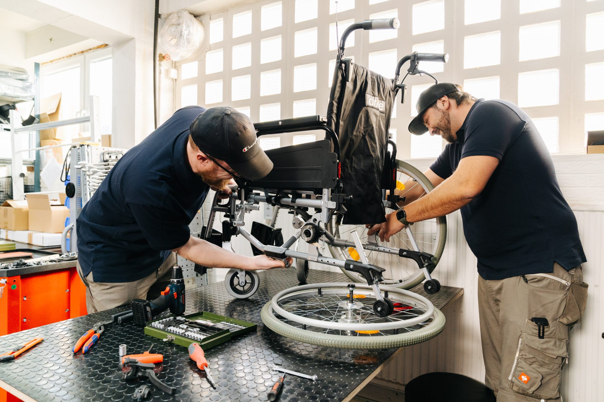 Two Carenetic technicians assembling a wheelchair together in the workshop