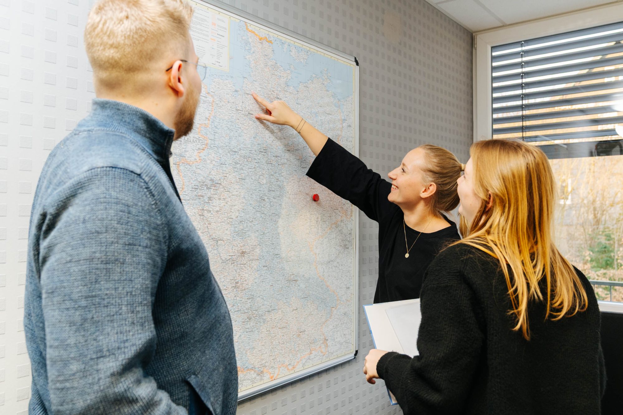 Carenetic team discussing the service areas in front of a map of Germany