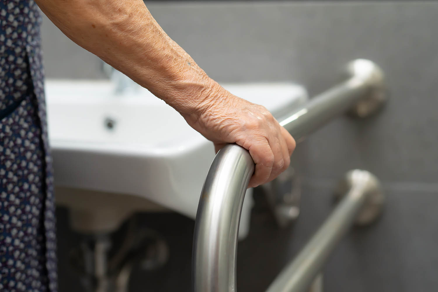 Eine Hand hält sich an einem Griff im Badezimmer fest