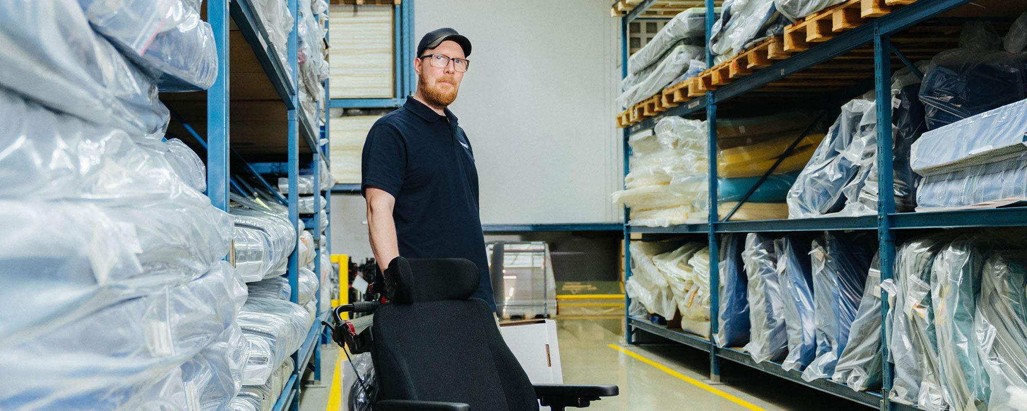 Carenetic employee pushing a wheelchair through the aids warehouse