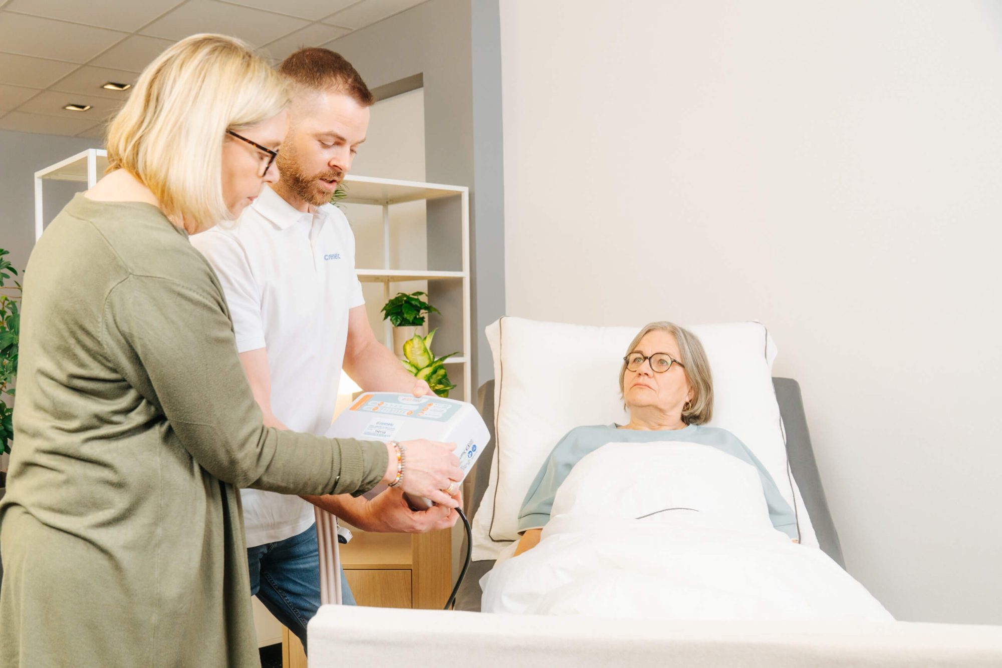 Carenetic Mitarbeiter erklärt einer Angehörigen die Handbedienung eines Pflegebetts